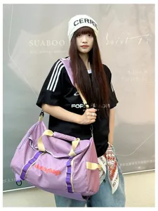 Close-up detail of a large purple travel duffel bag carried by a model outdoors