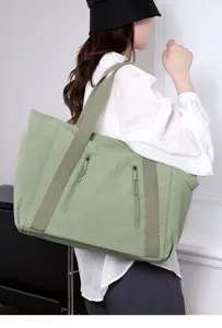 Detailopname van de grote groene nylon tote bag met dubbele ritsvakken en schouderbanden.