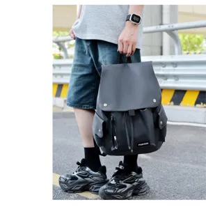 Grauer Rucksack Detailansicht mit Fronttasche, Metallknöpfen und strapazierfähigem Material.
