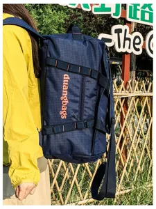 Large navy grid travel bag worn as a backpack in an outdoor camping park setting.