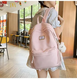 Pink campus style backpack detail shot, showing front pocket, fabric texture and cute pendant.