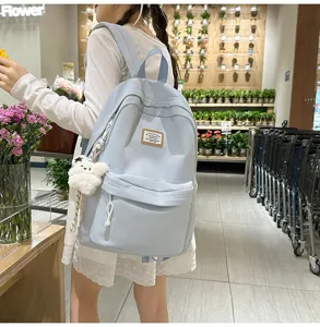 Detail shot of light blue casual backpack with plush bear pendant in store setting.