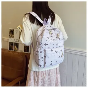 Mochila casual morada para mujer con estampado de lazos, gran bolsa escolar elegante para viaje.