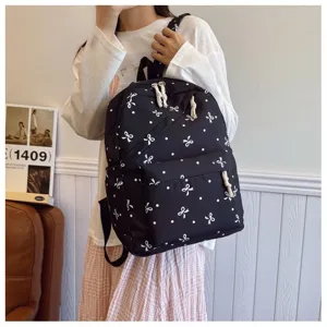 Primer plano de la elegante mochila negra con estampados de lazos blancos y correas.