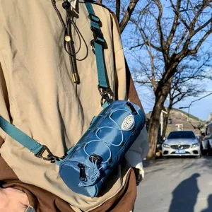Detailansicht der lässigen zylindrischen Umhängetasche, blaues Material mit Kordelzügen.