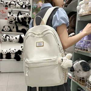 Casual white backpack for school and daily use with spacious compartments and cute pendant design.