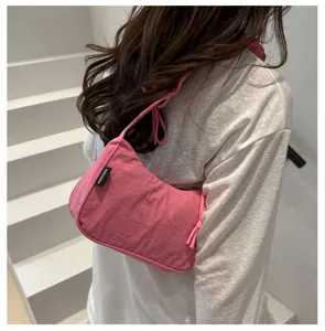 Detail view of a stylish pink pleated underarm bag worn by a model in a minimal setting
