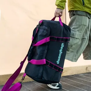 Large capacity outdoor camping storage bag in black with vibrant magenta straps shown in use