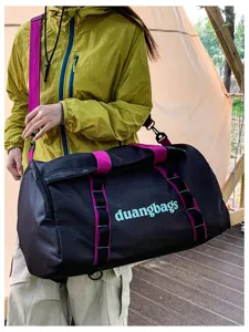 Outdoor camping travel duffel bag with magenta straps shown being used in nature