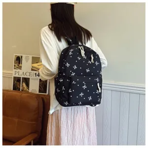 Vista detallada de la mochila negra informal con bonitos estampados de lazo blancos.