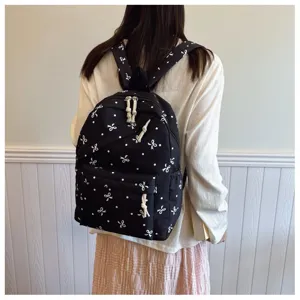 Vista detallada de la elegante mochila negra con bonitos lazos blancos y lunares.