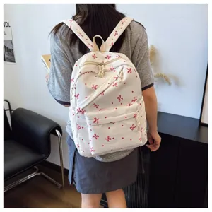 Mochila de lona blanca con diseño de lazo rojo, espaciosa para uso diario y viajes.