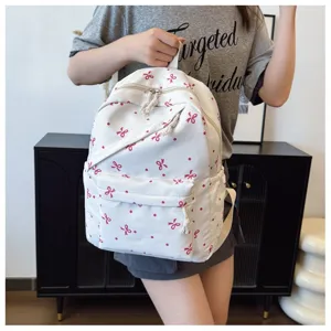 Vista detallada de mochila informal blanca con bonito estampado de lazos rojos y lunares.