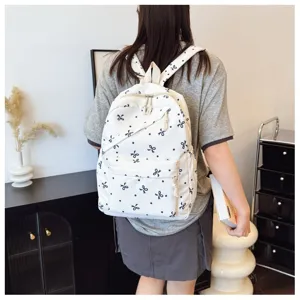 Mochila blanca casual con lazos y lunares negros, ideal para la escuela y viajes diarios.