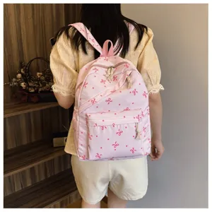 Detalle de mochila rosa con bonito diseño de lazos y práctico bolsillo frontal con cremallera.