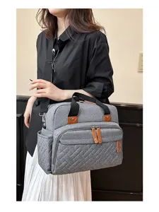 Large capacity gray textured diaper bag with multiple pockets and leather accents shown on model