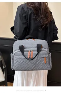 Detailed view of a grey quilted mommy bag featuring multiple pockets and leather accents