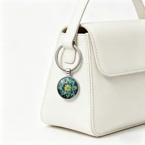 Detailed view of a blue and gold mandala keychain hanging on a white leather handbag