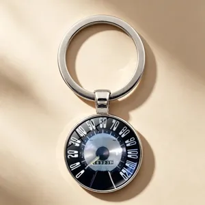 Close-up of a vintage car speedometer keychain with a metal key ring and glass pendant.
