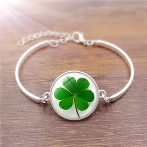 Detailed shot of a silver clover glass cabochon bracelet on a wooden background