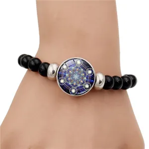 Gros plan d'un bracelet en perles noires avec un charme mandala cube de Métatron