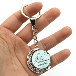 Detail of a rotating silver moon keychain with Bible verse Luke 1:37 inscription.