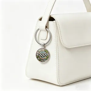 Close-up of metal 888 lucky number keychain with four-leaf clover hanging on white handbag