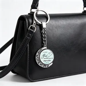 Close-up of a rotating silver moon keychain with a Bible verse on a black bag