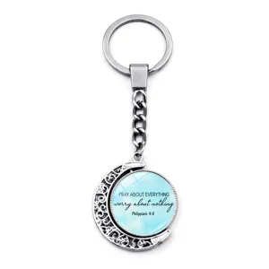 Macro view of silver rotating moon keychain with Philippians 4:6 bible verse text
