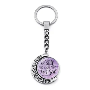 Close-up of rotating moon keychain with inspirational Psalm 46:10 quote on purple background