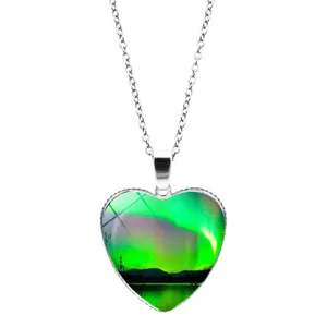 Detailed view of heart-shaped pendant necklace with vibrant green aurora borealis night sky art