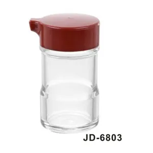Close-up detail of acrylic condiment dispenser with red lid and pour spout