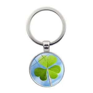 Detailed view of the round glass keychain featuring a green clover and blue sky motif.