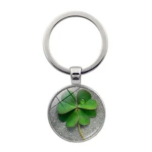 Close-up detail of a lucky four-leaf clover keychain with green plant glass cabochon