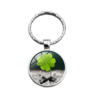Détail d'un porte-clés en verre argenté avec un motif trèfle à quatre feuilles vert.
