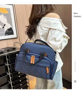 Detailed view of navy blue quilted diaper bag with multiple zipper pockets and shoulder strap