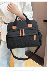 Detail view of stylish black quilted diaper bag featuring multi-pockets and adjustable strap