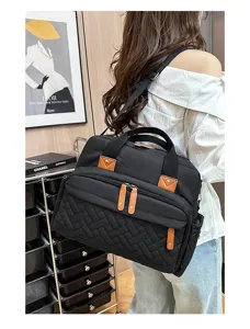 Large black quilted diaper bag with multiple pockets shown on shoulder for travel