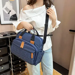 Large navy blue diaper bag with multiple pockets shown on an Asian female model.