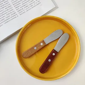 Detailed macro shot of two retro wooden handle butter knives resting on a vibrant yellow plate