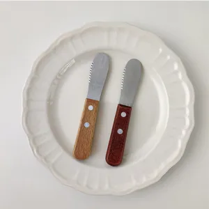 Set of two stainless steel butter knives with wooden handles on a white plate