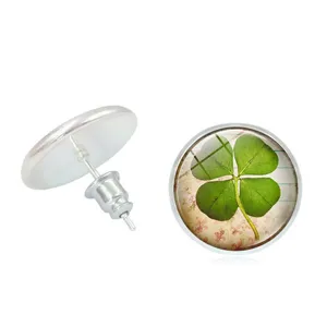 Detailed view of silver-toned four-leaf clover time gem stud earrings on white background