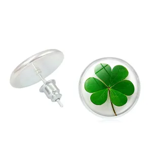 Detailed view of silver-tone stud earrings with a green four-leaf clover under glass