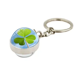 Close-up of a silver keychain pendant featuring a vibrant green clover under a crystal dome