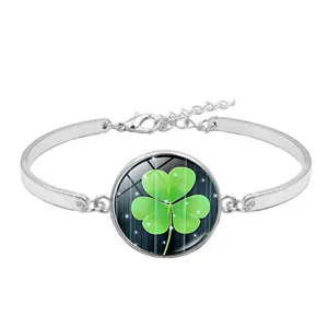Detailed macro view of a silver lucky clover bracelet with a green glass gemstone charm