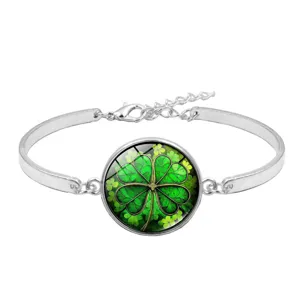 Close-up of a silver-toned bangle featuring a green four-leaf clover glass cabochon.