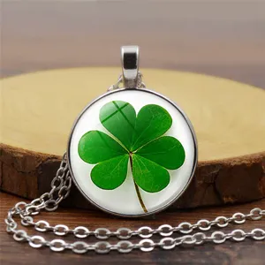 Collar plateado con colgante de vidrio de trébol de cuatro hojas verde en madera