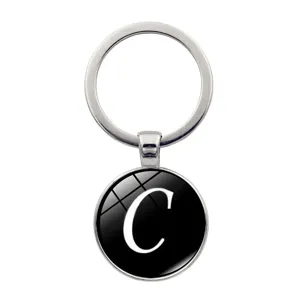 Detailansicht eines silbernen Metallschlüsselanhängers mit einer schwarzen Glaskuppel und dem C.