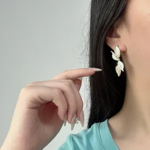 Primo piano di eleganti orecchini a forma di foglia con cristalli scintillanti.