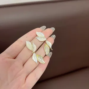 Primo piano di eleganti orecchini a lobo a foglia con smalto bianco e strass brillanti